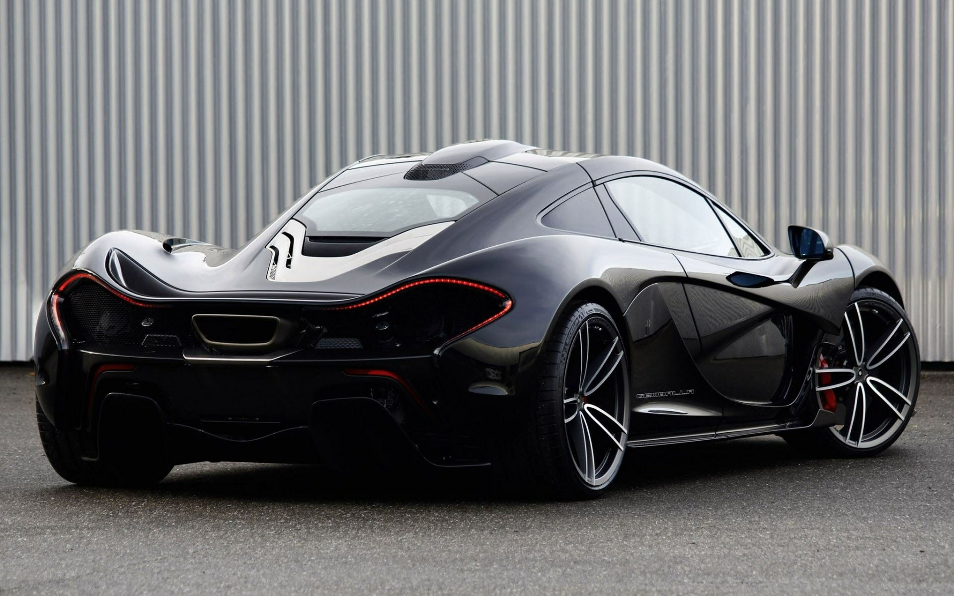 Wallpaper #hXOWg44BFI5NbQks1Buy36 A Sleek Black Mclaren P1 Parked in Front of a Corrugated Metal Wall