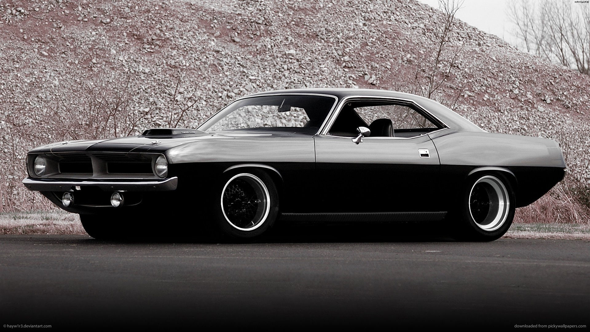 Wallpaper #lnOZg44BFI5NbQks9htG59 A Black 1970 Plymouth Barracuda Parked on a Paved Road Next to a Rocky Hill