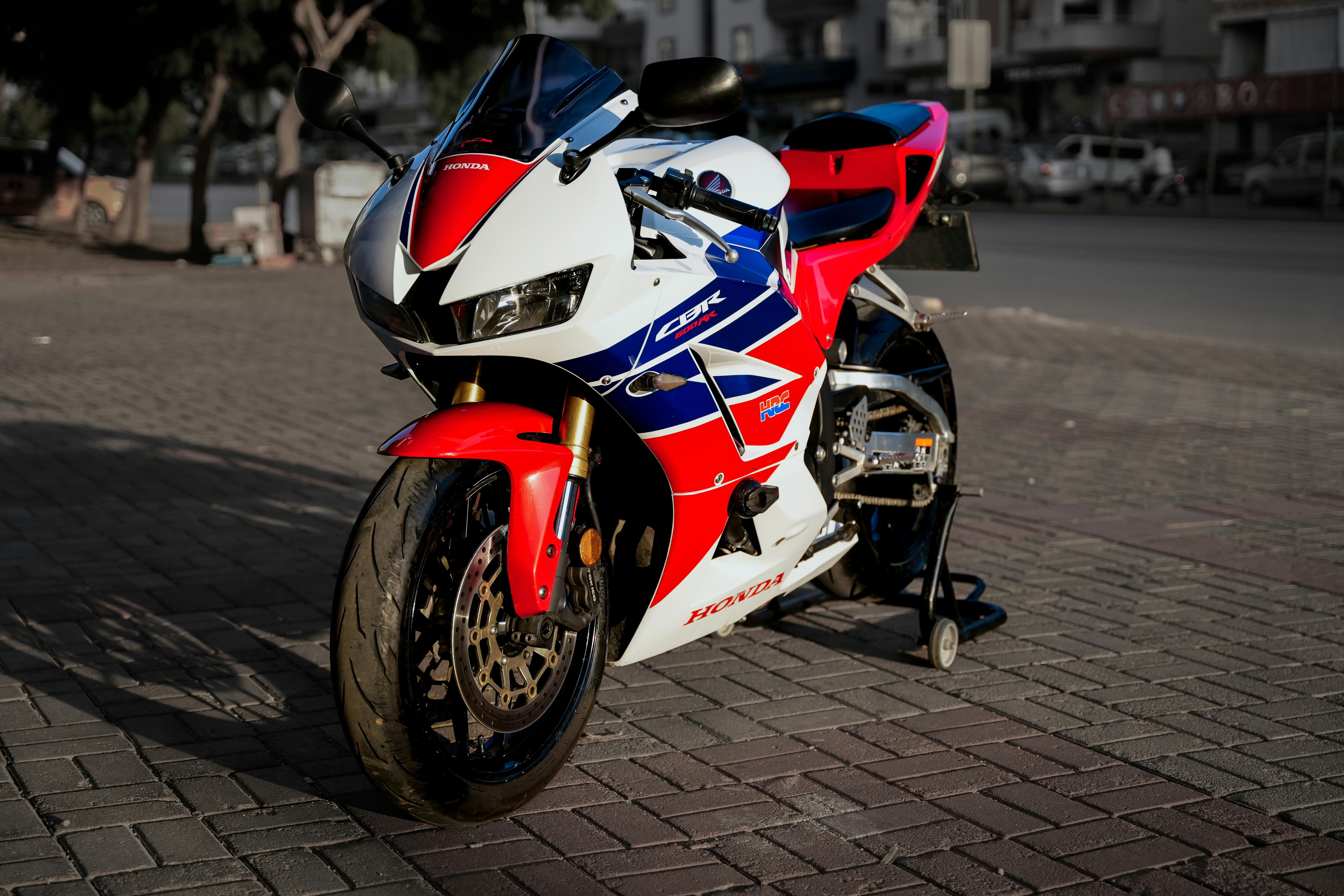 Wallpaper #_bkg35IBJvJKYCmE2wi4484 Sleek Honda Racing Motorcycle in Sunlit Urban Setting Free Stock Photo
