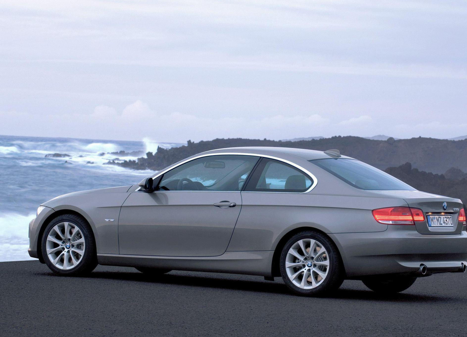 Wallpaper #lUW_oo4B7YBJg1BVBqSA49 A Silver BMW Parked on a Coastal Road with the Ocean in the Background