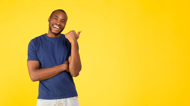 Wallpaper #IWf6_JIBSpphPi3-lZoB128 Premium Photo Cheerful Black Man Pointing Thumb at Copy Space Yellow