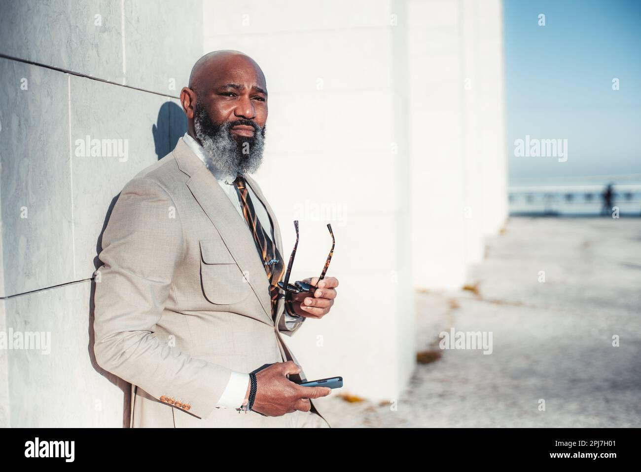 Wallpaper #IWf6_JIBSpphPi3-lZoB314 A Stylish Black Man with a Bald Head and Full Beard Holding a Phone