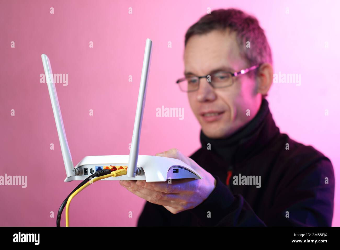 Wallpaper #-Wdg_JIBSpphPi3-fJf6325 A Person Holding a White Router with Two Antennas on a Pink Background