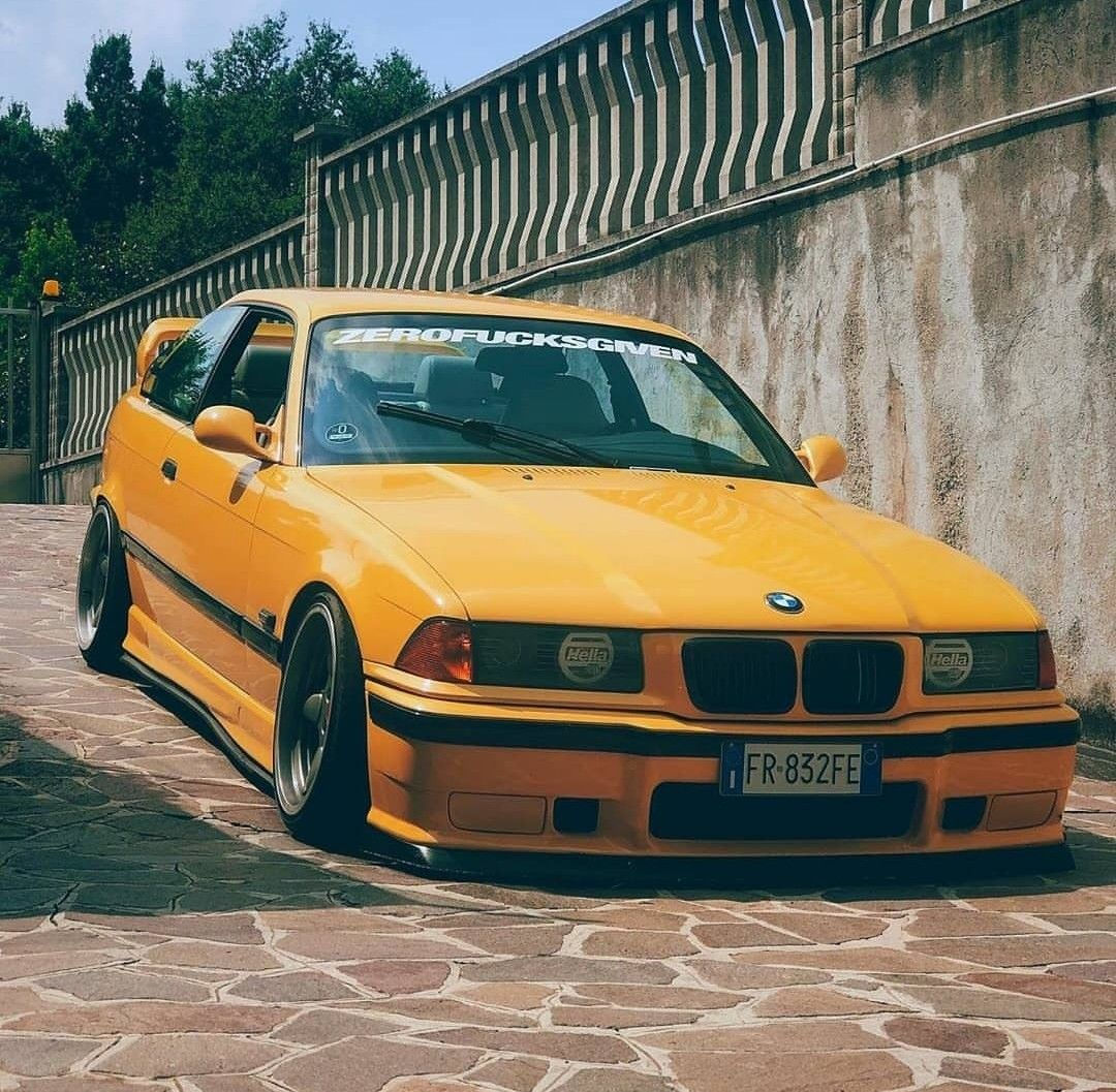 Wallpaper #5WfP75IBSpphPi3-NWNY162 A Yellow Car Parked on the Side of a Road Next to a Stone Wall and Fence