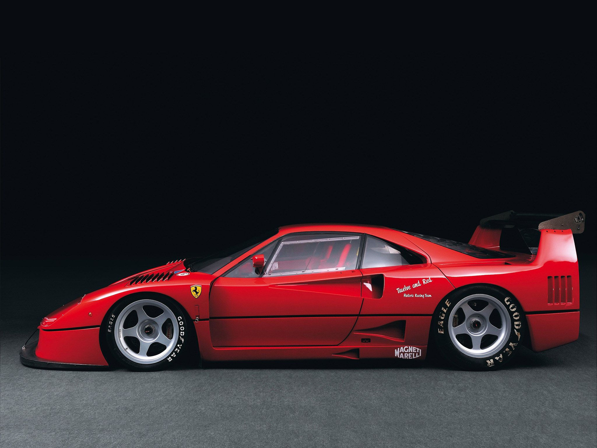 Wallpaper #U3Tzwo4B_8f4nGFavG-Q18 A Red Sports Car Parked on Top of a Gray Floor Next to a Black Wall