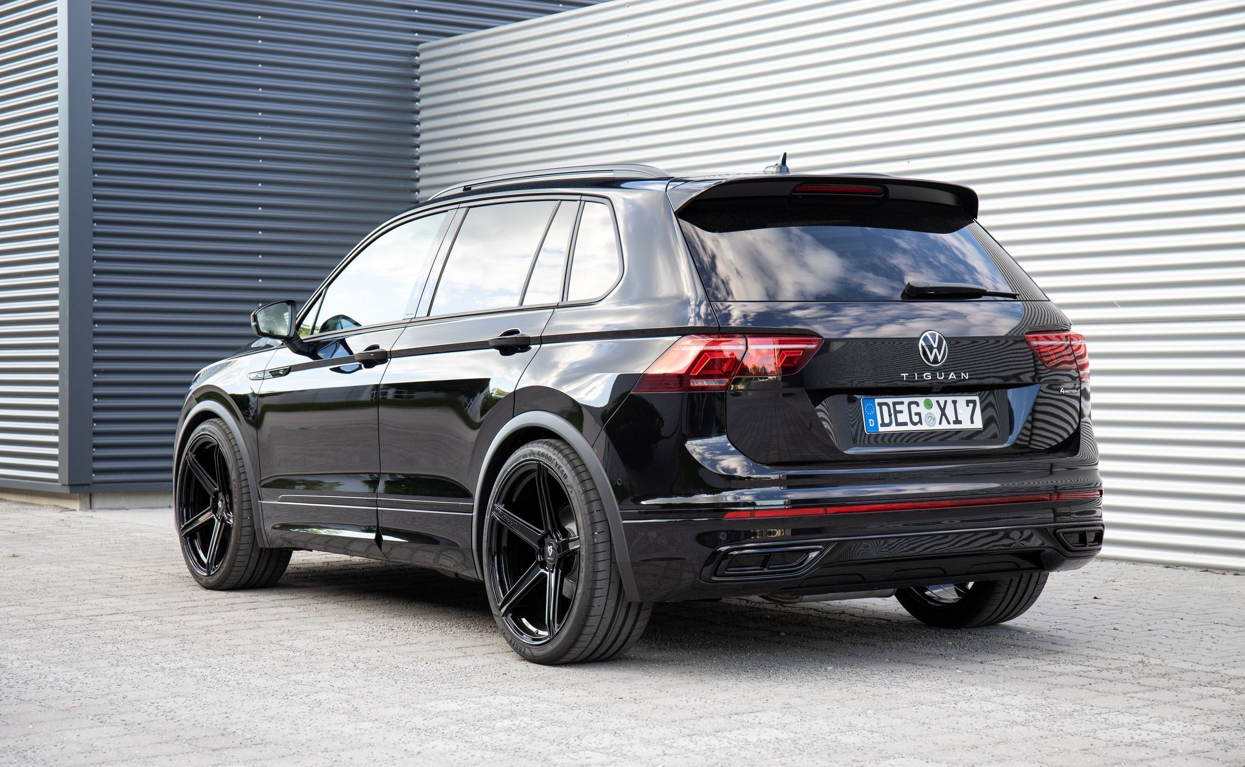 Wallpaper #VuoBU5MBlwTYPL18ogqa334 The Rear End of a Black Volkswagen SUV Parked in Front of a Garage Door