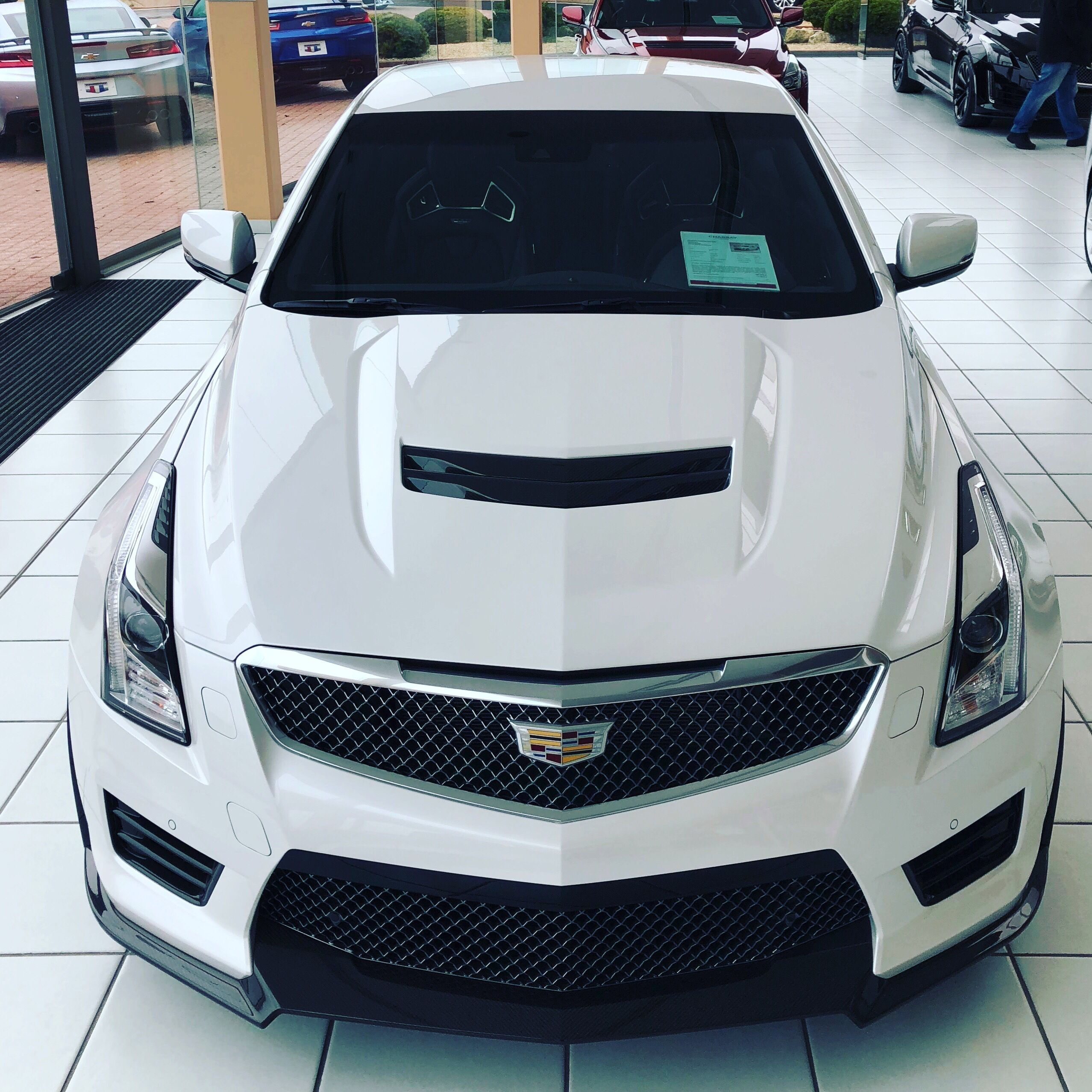 Wallpaper #9hnGDo8BtGB6xQ78ZlrT47 The Front End of a White Car in a Showroom