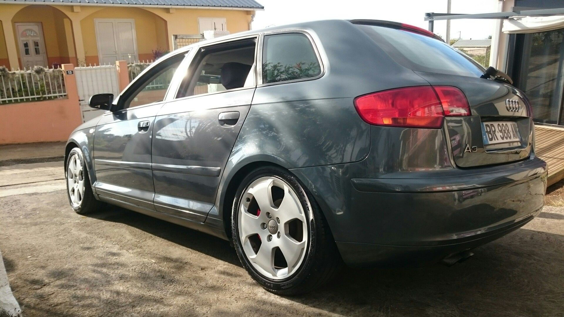 Wallpaper #-GfS5pIBSpphPi3-8DTR432 The Rear End of a Gray Car Parked in Front of a Yellow House with White
