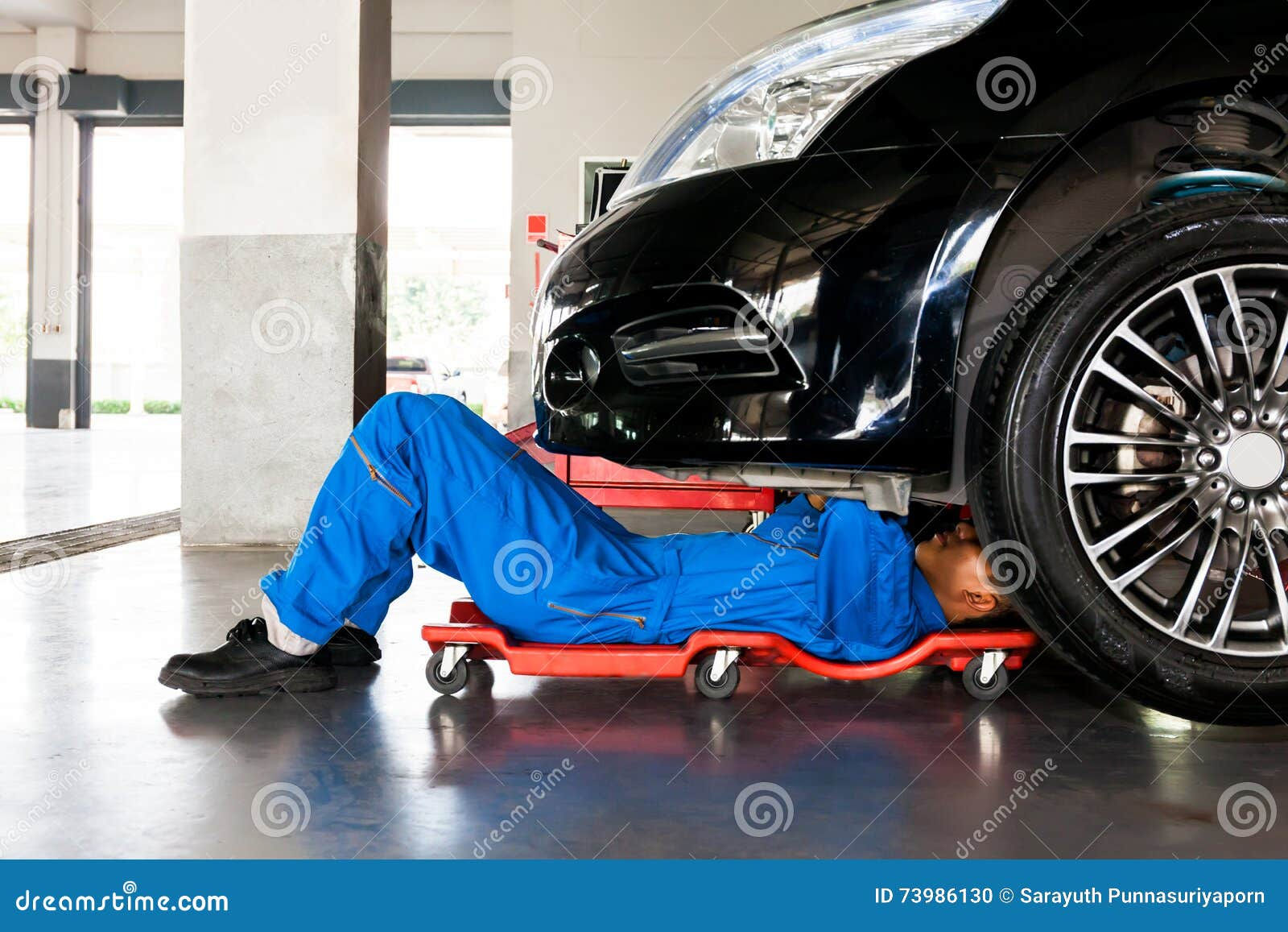Wallpaper #F0IWPZMBOBpx0Nhm38Og139 Mechanic in Blue Uniform Lying Down and Working Under Car at Auto