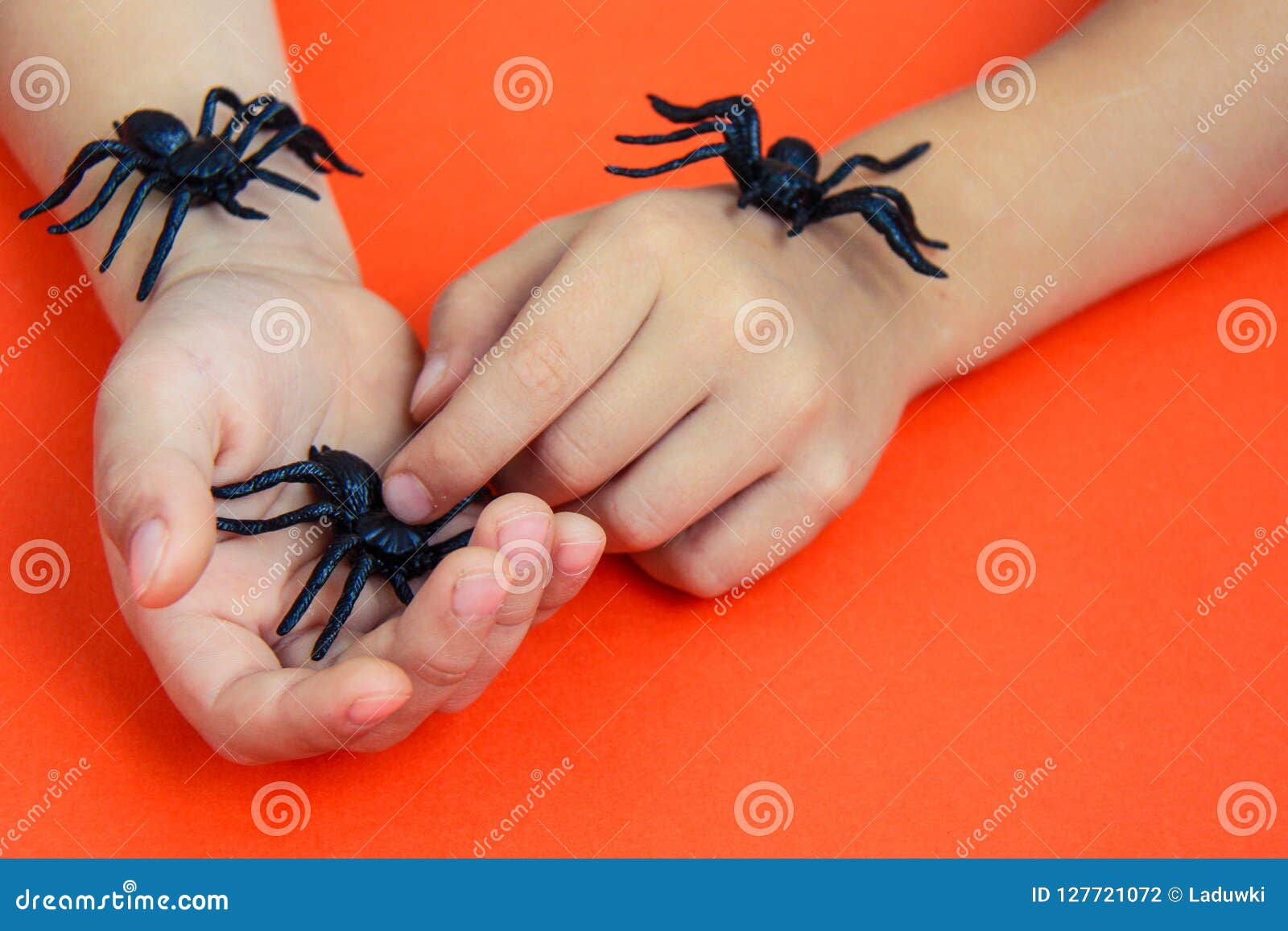 Wallpaper #1fQOOpMBKFX8bn3r-3cr158 Hands of a Child Playing with Black Rubber Spiders Toys on Orange Paper