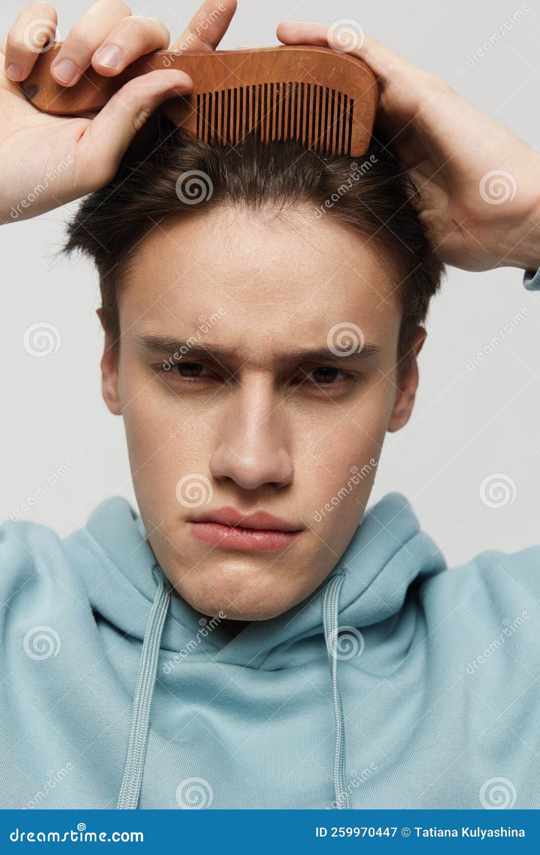 Wallpaper #VmjCH5MBSpphPi3-_iwa384 A Strange Frowning Young Man Combs His Hair in a Light Light Blue