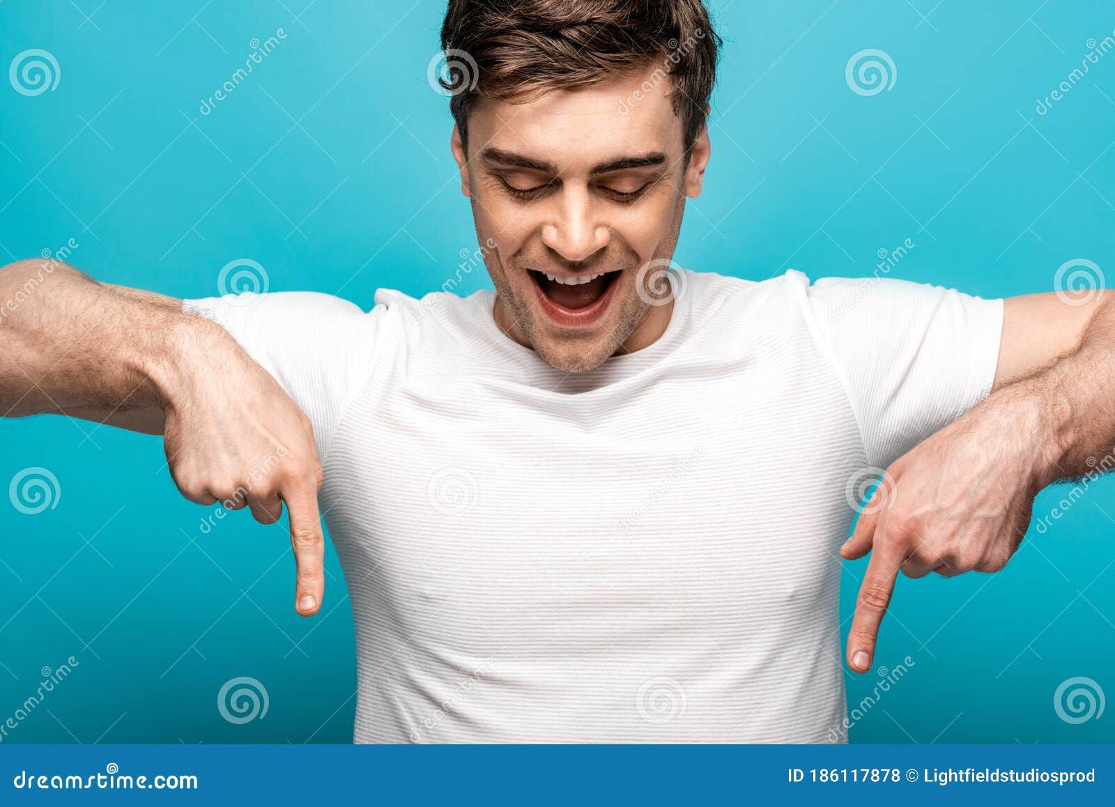 Wallpaper #xRldDo8BtGB6xQ784lmF40 Young Man Pointing Down with Fingers on Blue Background Stock Photo
