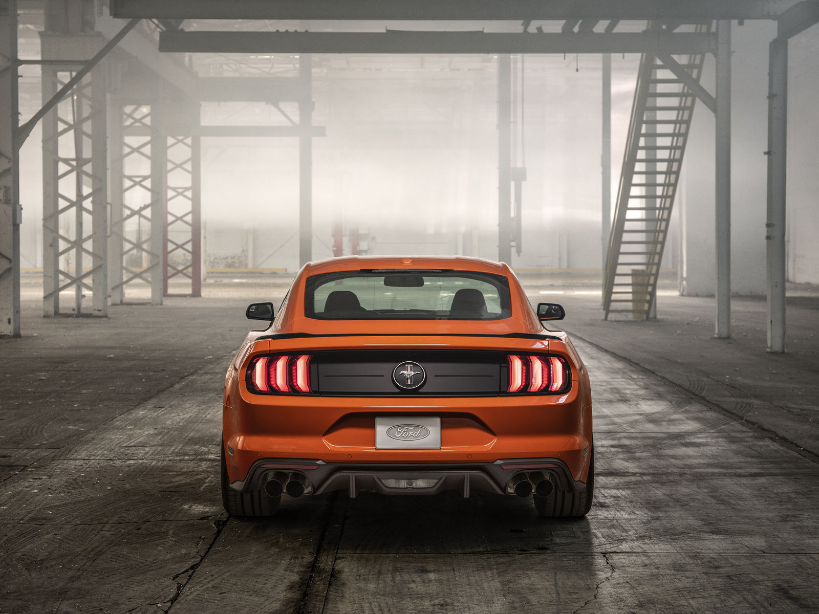 Wallpaper #_kWjoY4B7YBJg1BVvqN846 A Sleek Orange Ford Mustang Parked in an Industrial Setting