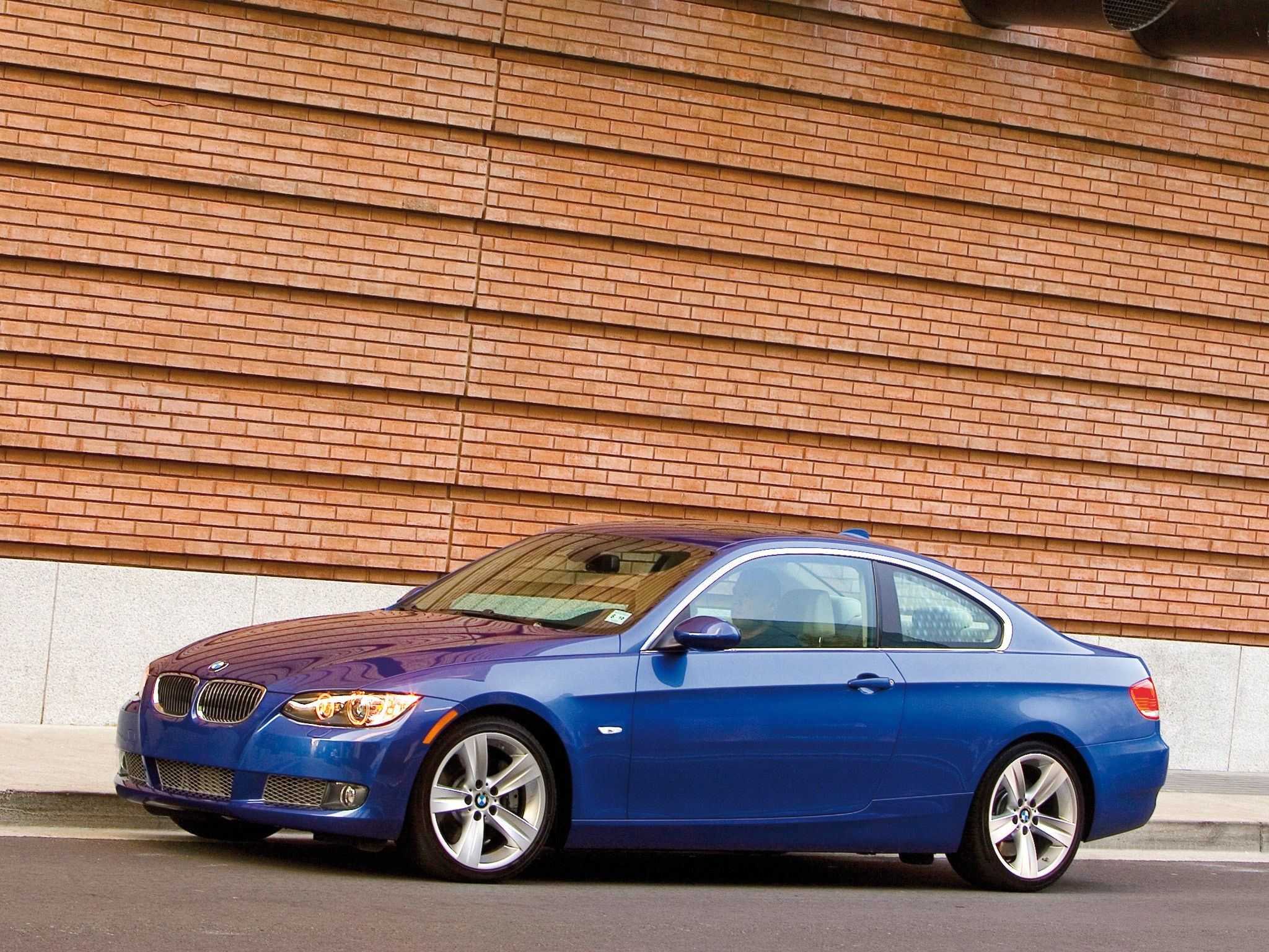 Wallpaper #lUW_oo4B7YBJg1BVBqSA51 A Sleek Blue BMW Parked in Front of a Brick Building